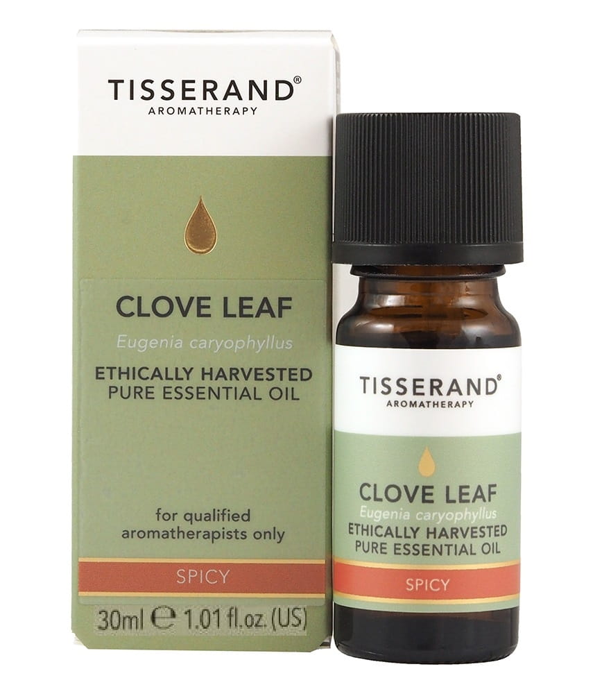 Ethisch geerntetes Nelkenöl in 30 ml Flasche von TISSERAND AROMATHERAPY, mit Nelkenblättern im Hintergrund